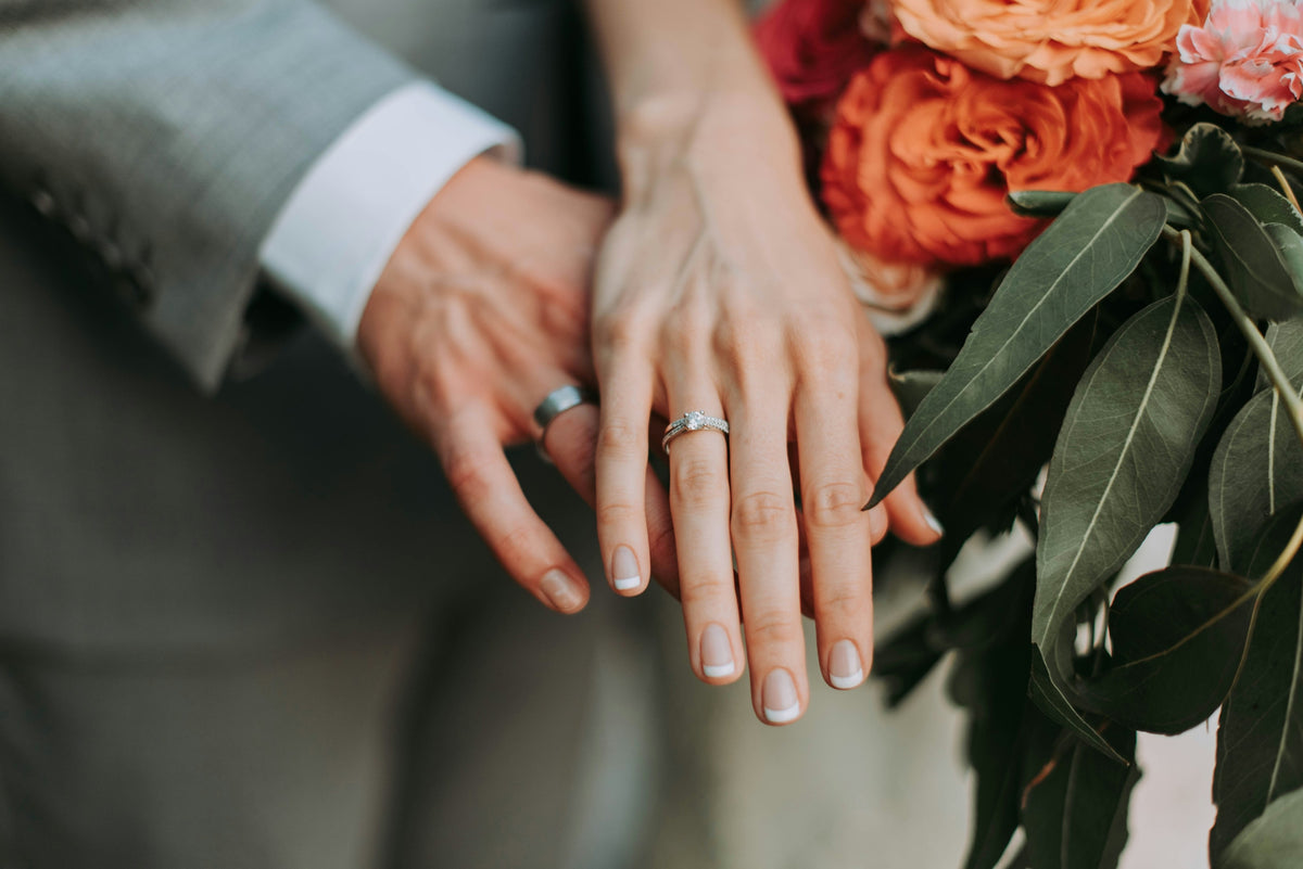 A couple's hands wearing rings, with roses