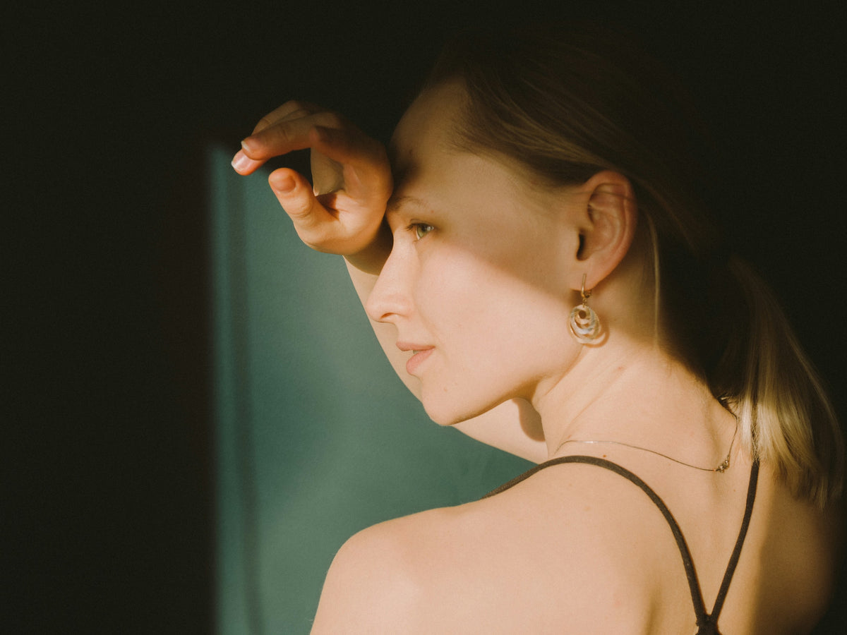Woman in warm window light wearing a gold drop earring