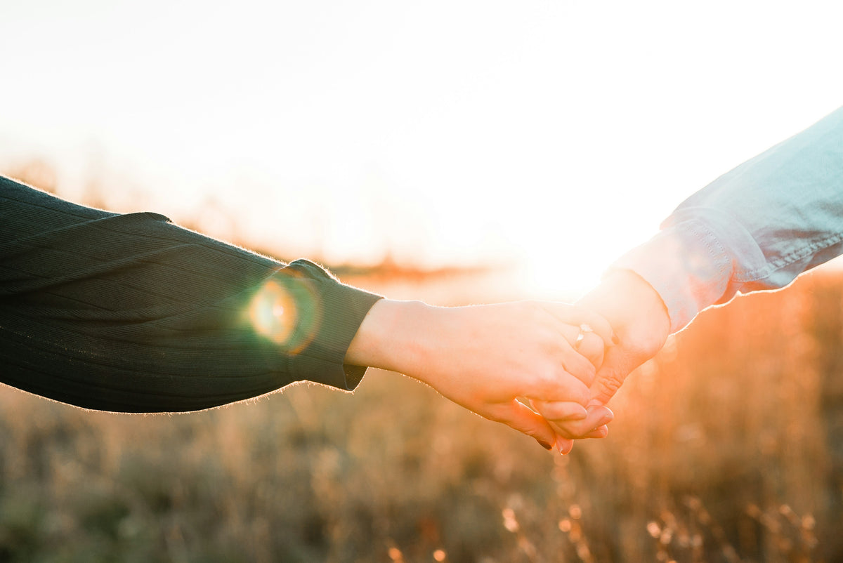 Two hands reaching for each other in golden light