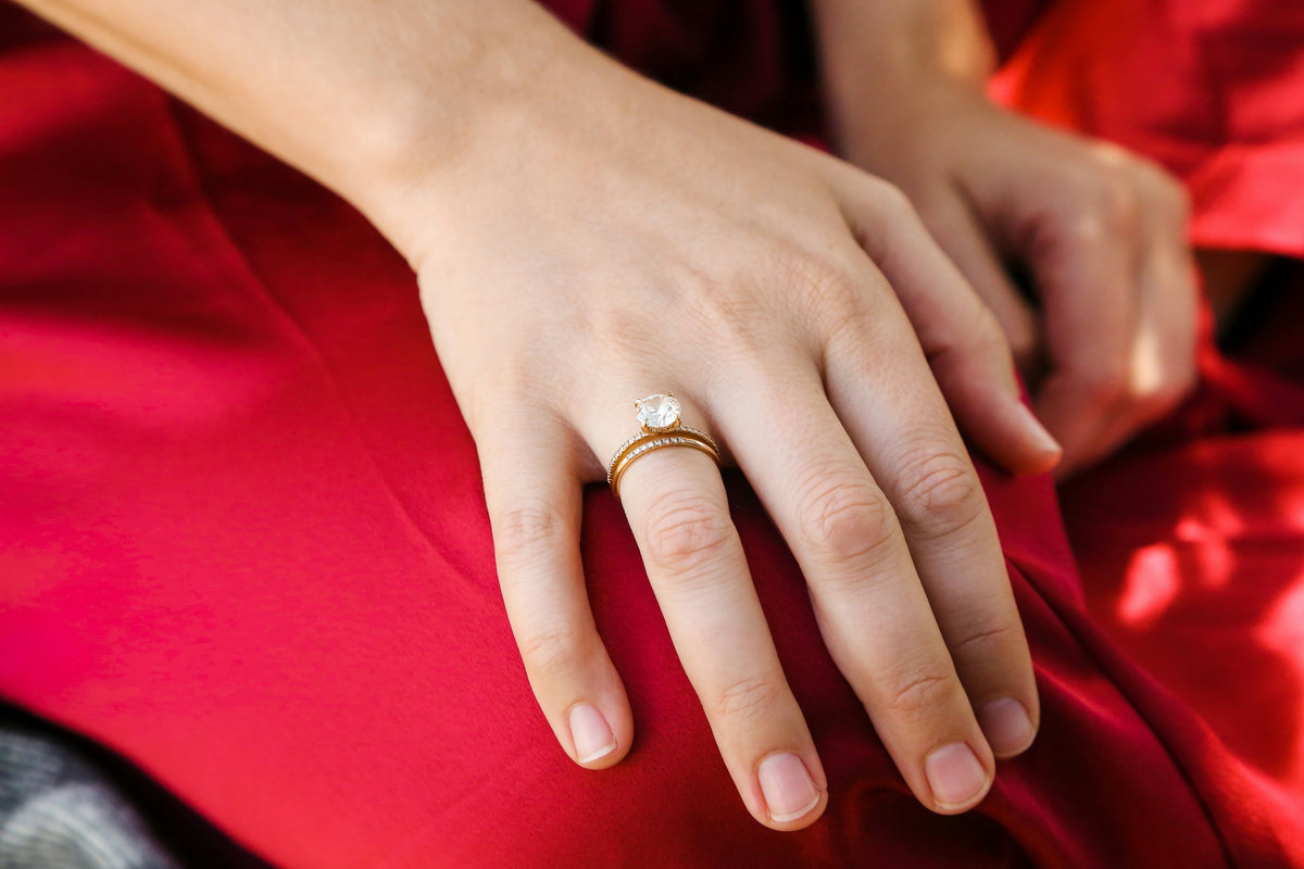 Hand wearing a diamond ring resting on burgundy silk